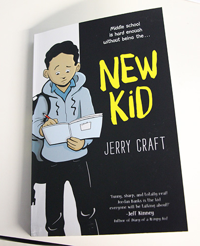 A picture of a book that has a drawing of a middle school kid on it in a hoodie with a backpack. He is reading but his face looks sad. It says New Kid by Jerry Craft