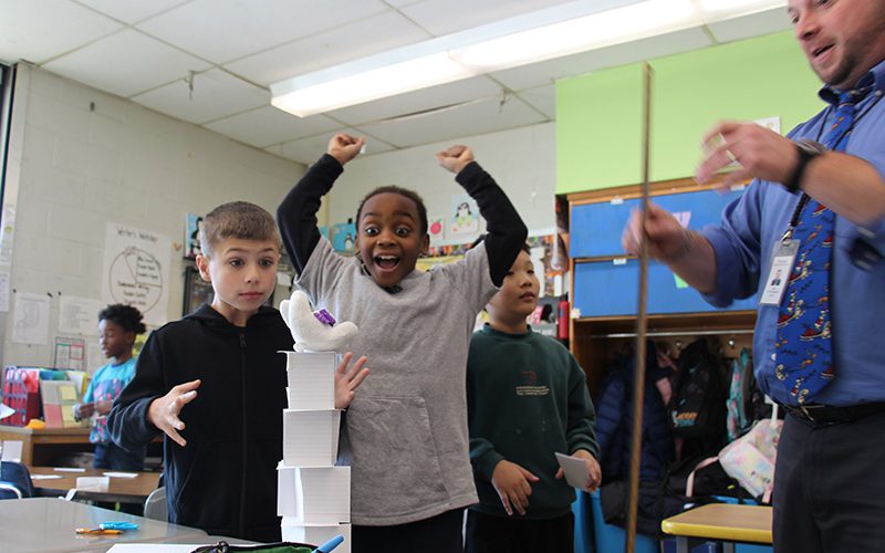 Third grade students shakes hands with man while accepting his new dictionary