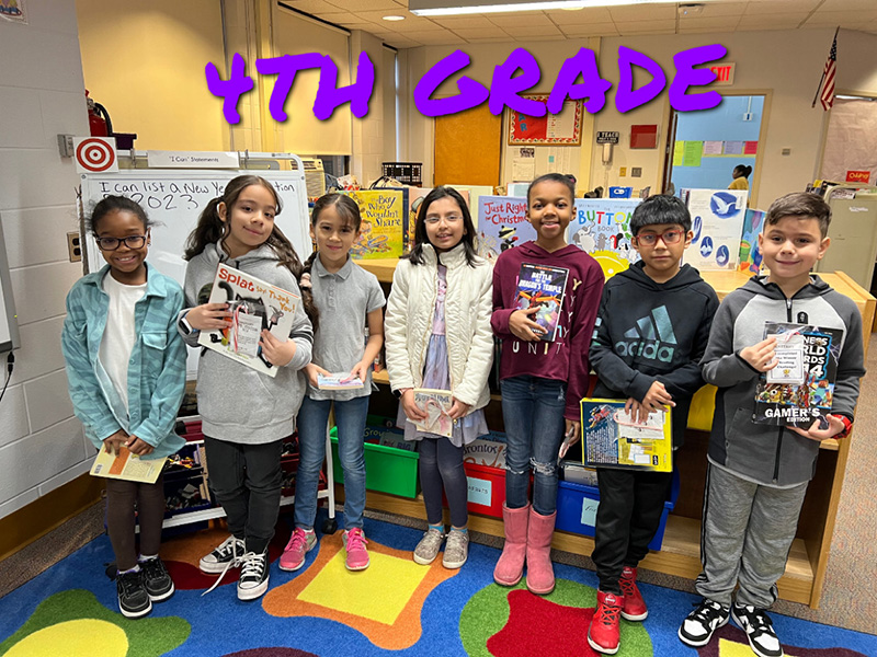 A group of seven fourth-grade students standing together. Each is holding a book.