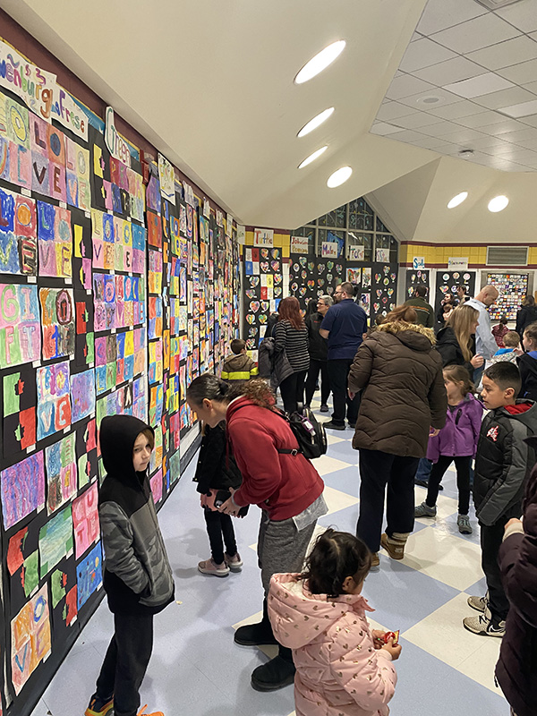 Many people look at a wall of artwork.
