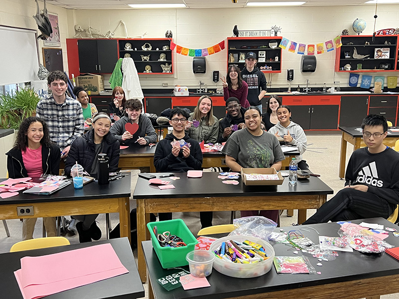 Tables of high school students sit and make valentines.
