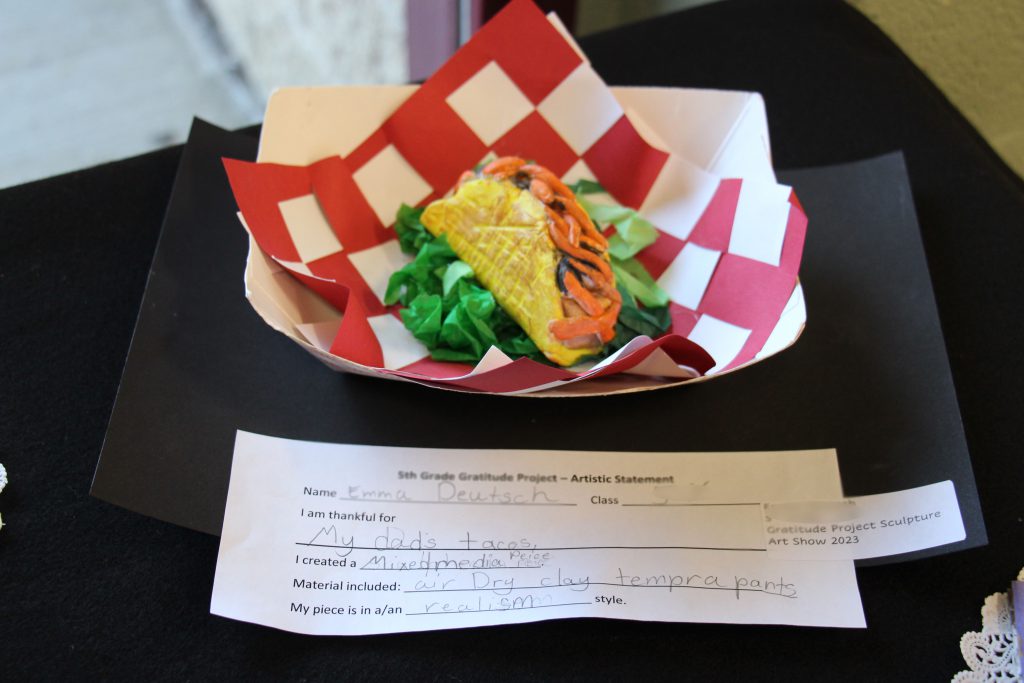 A sculpture of a taco on a red and white napkin in a paper holder.