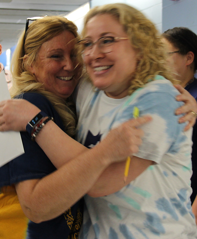 Two women, both with blonde hair, hug each other.