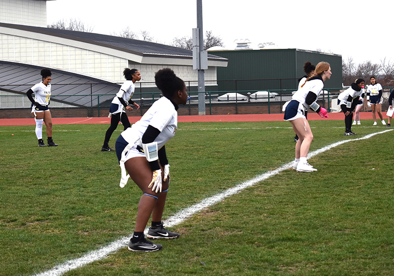 Six high school girls stand along a line of scrimmage waiting for a play to begin.