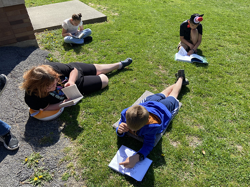 Students read outside in the grass