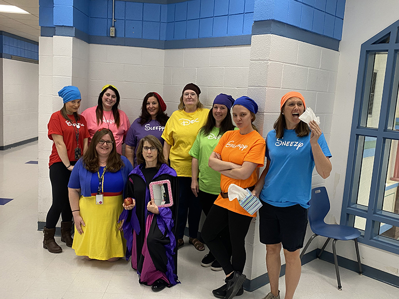 A group of nine women dress as snow white and the seven dwarfs and a witch.