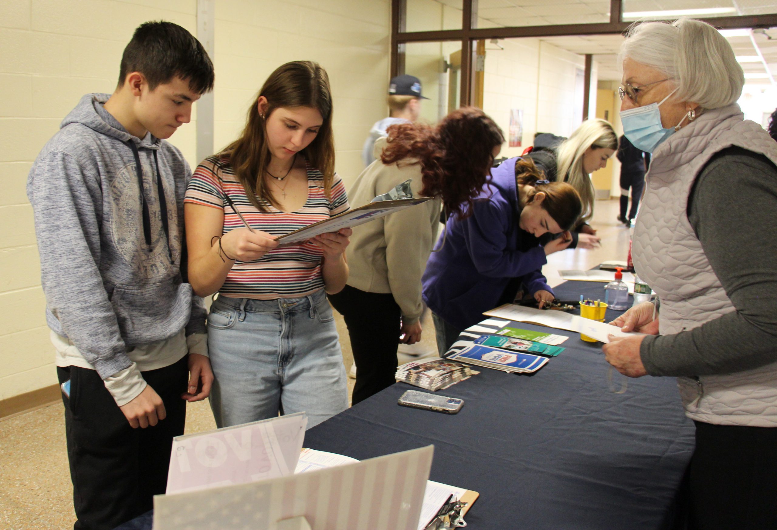 Several high school students complete forms at a table.