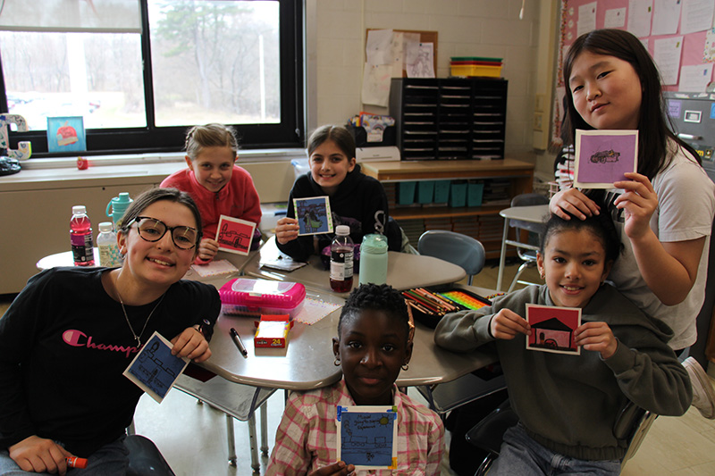 A group of six fifth-graders hold up little squares they colored.