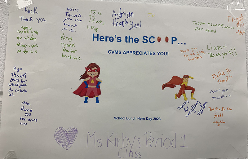 A poster - white background with two super heroes on it, a woman and man. It says Here is the Scoop - CVMS Appreciates you. There is writing all around the poster with kids thanking the woerkers.