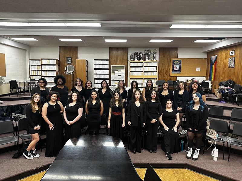 A large group of high school students, all wearing black, stand in two rows.