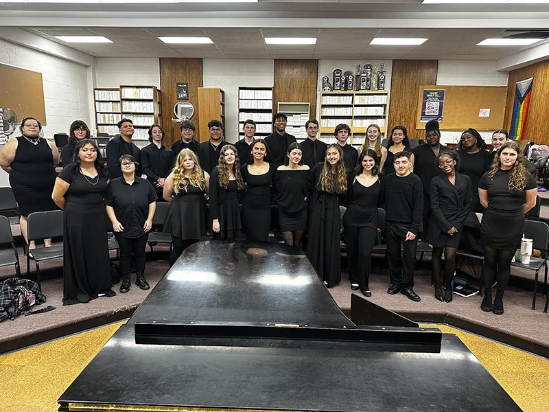 A large group of high school students, all wearing black, stand in two rows.