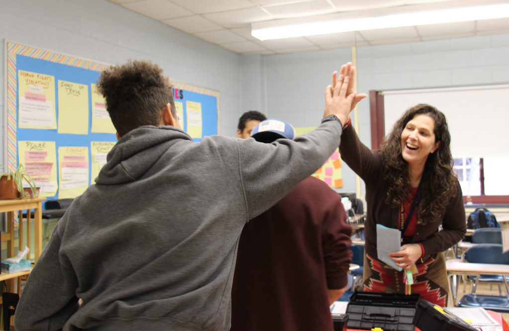 A woman high fives a high school student after the student gave an answer.