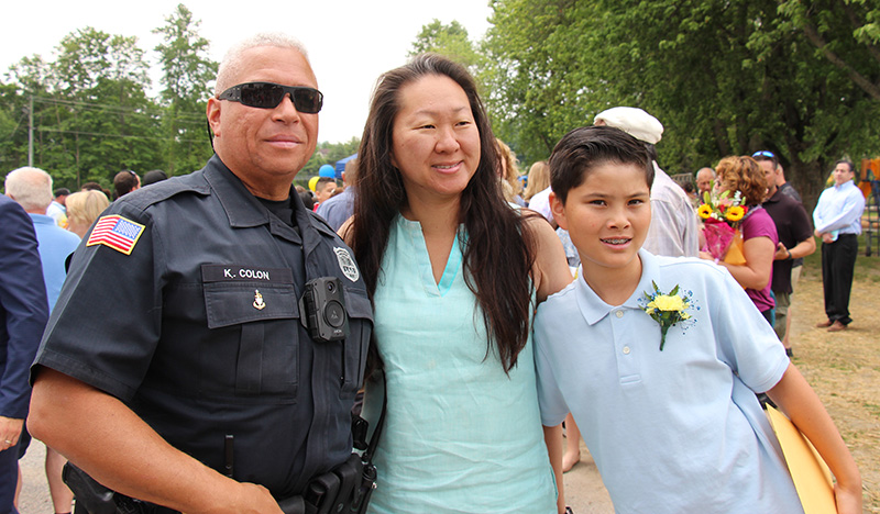 A fifth-grade boy stands with a woman and man.