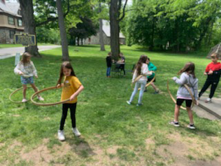 Girls are standing at a distance from each other doing hula hoops