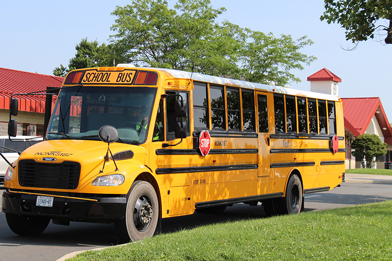 A large yellow school bus in front of a school building.