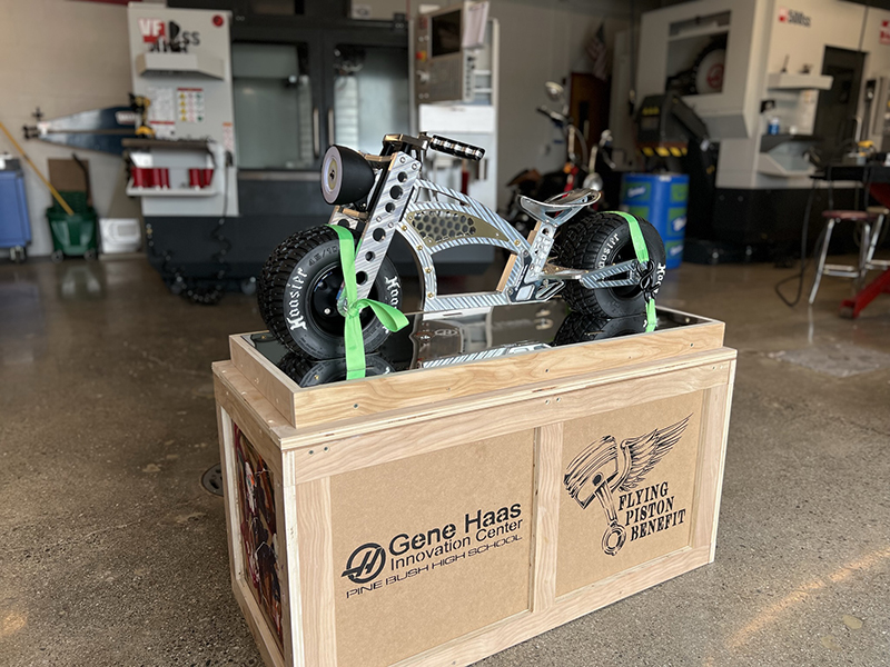 A small metal bike sits atop a large wooden case. 