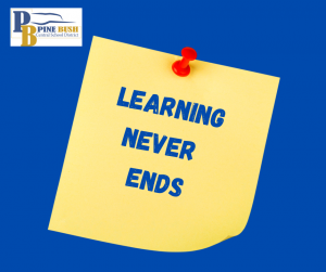 A blue background with a yellow post-in note held by a red push pin. On the note says Learning Never Ends. There is a PB logo in the upper left corner.