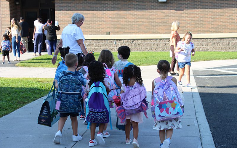 A group of pre-K students walk along with an adult.