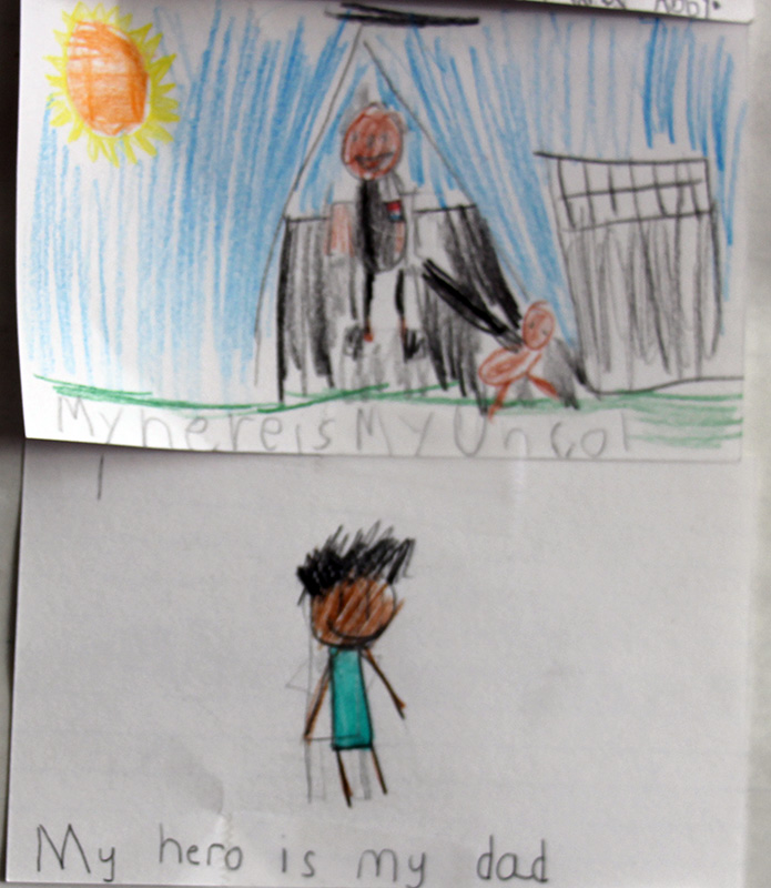 White cards with drawings of people on them drawn by third grade kids.