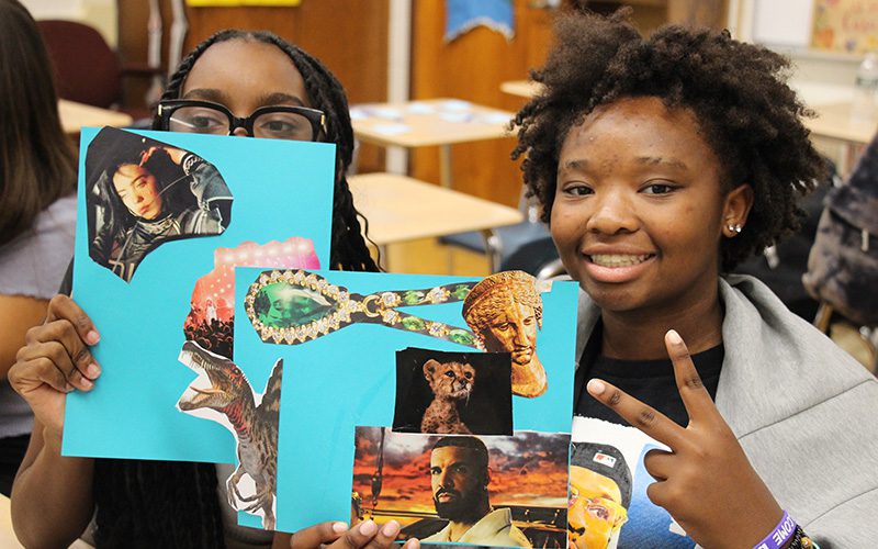 Two high school girls hold up their vision boards, made up of photos they cut out of magazines.