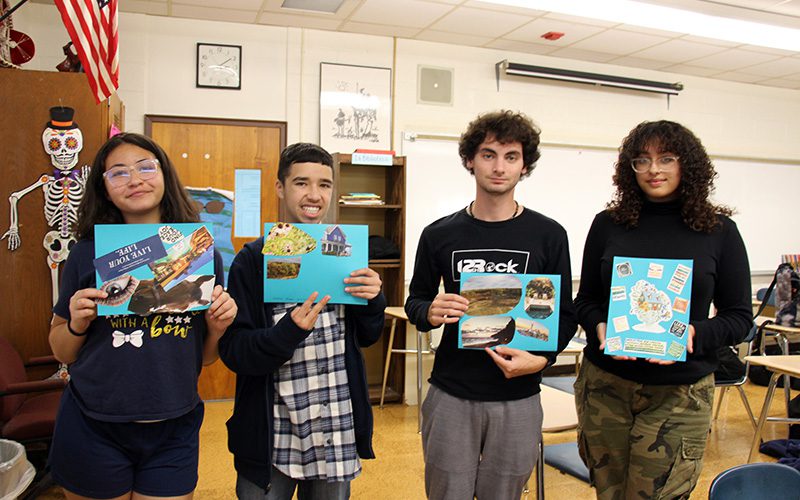Four high school students hold up their vision boards. They are smiling.