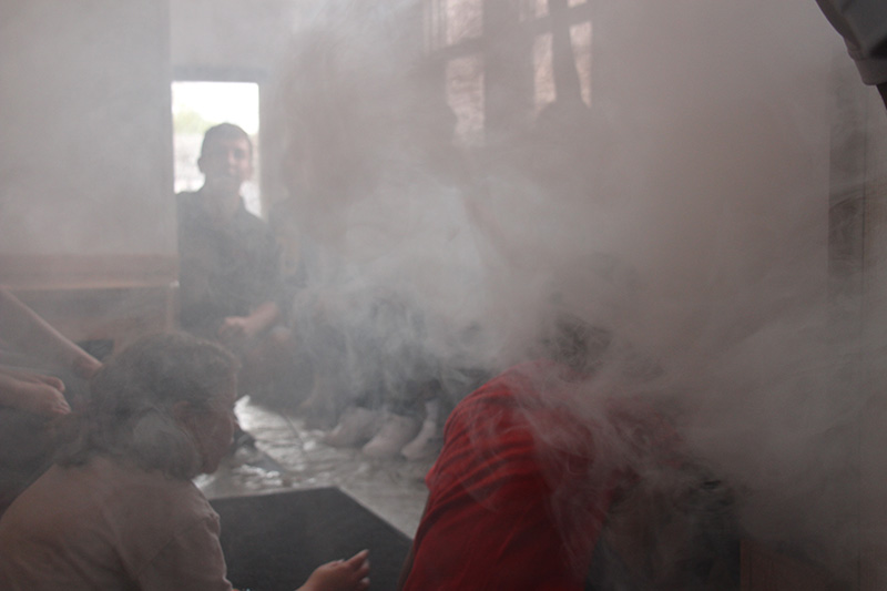 Smoke fills a small room where fifth-grade students are seated and a firefighter talks to them. 