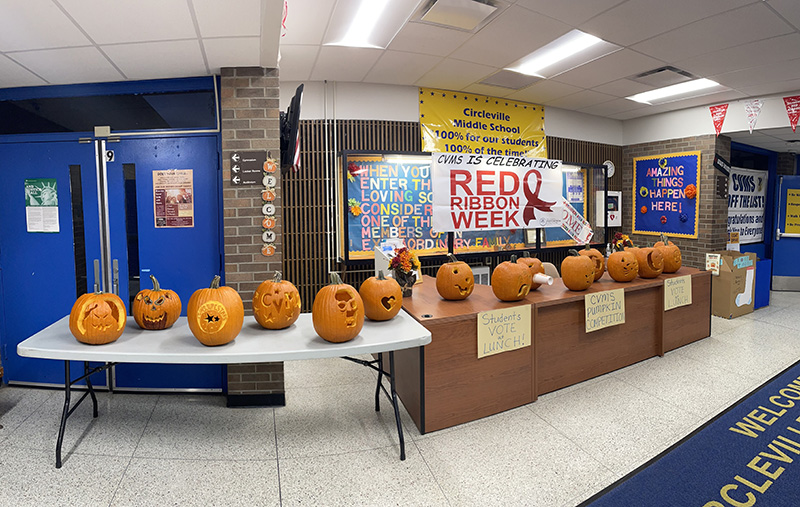 Two long tables with carved pumpkins on them.