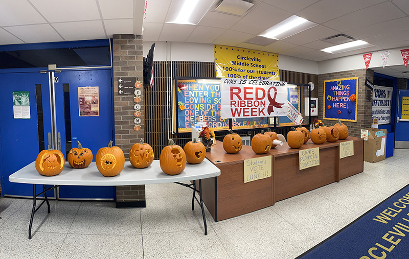 Two long tables with carved pumpkins on them.