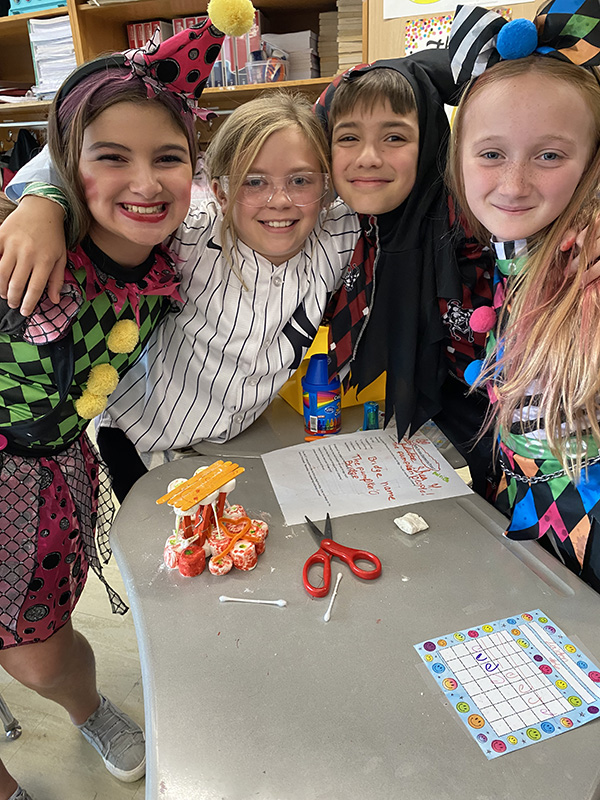 Four girls are arm in arm with their homemade bridge in front of them.