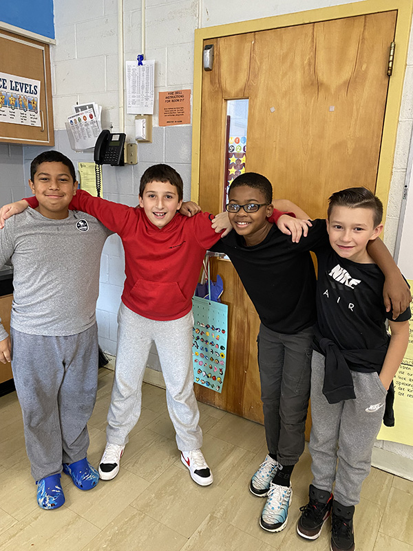 Four boys are arm in arm and smiling.