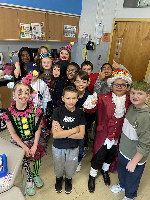 A large group of fifth-grade kids stand together and smile.