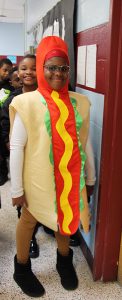 A fourth grade students dressed in a hot dog costume.