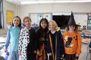 Four fourth[-grade students stand together in their Halloween costumes.