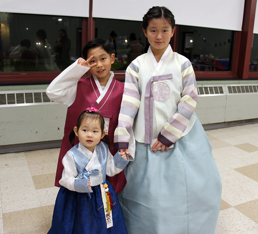 Three children dress in traditional Asian dress.