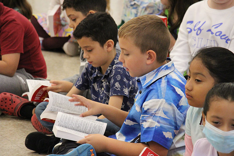 Two third grade boys sit on the floor and look at their dictionaries.