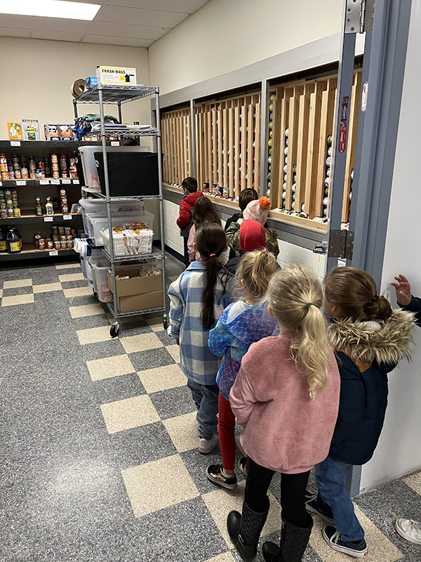 A line of kindergarten students go into a food pantry for a tour.