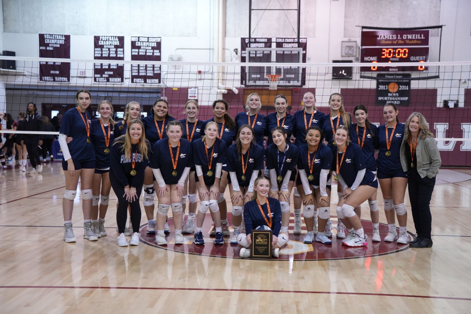 A volleyball team in two rows all with medals around their necks. They are smiling.
