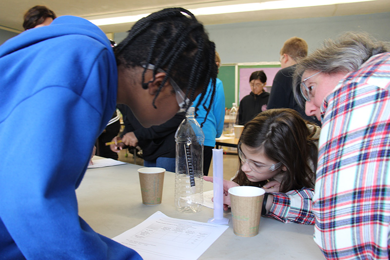 Two third-graders look closely at the temperature strip in the clear plastic bottle they are working with.