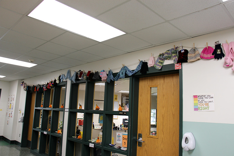 Outside of an office above the door and windows hang a line of mittens, gloves, hats and scarves.