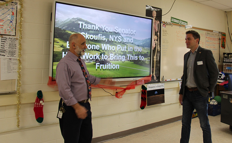 Two men flank a large display screen that Says Thank you New York State Senator James Skoufis.