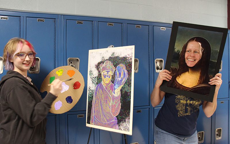 A high school girl with multi-colored hair holds a artist's pallete and is painting a photo. Next toher is a woman whose face is in place of the Mona Lisa.