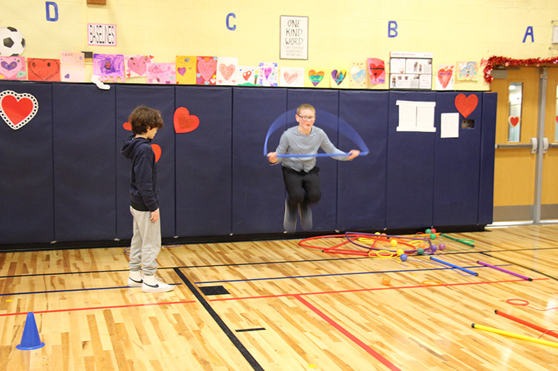 An elementary student jumps rope while another watches.