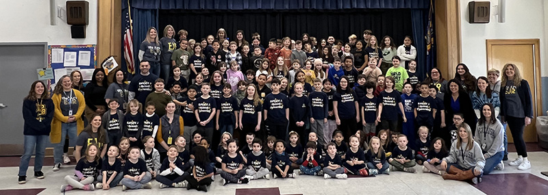 A large group of elementary school kids and adults on a stage.