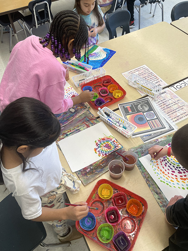 elementary students are painting with many colors.