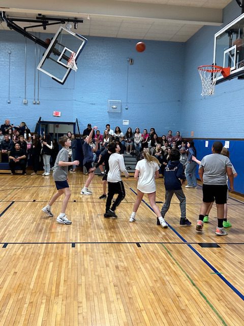 A group of middle school kids play basketball.