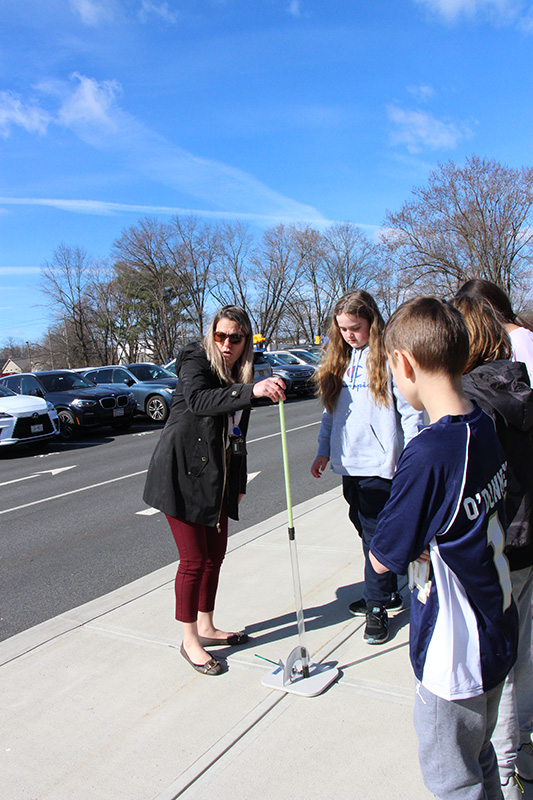 An elementary-age girl stands with a woman waiting to launch a straw rocket.