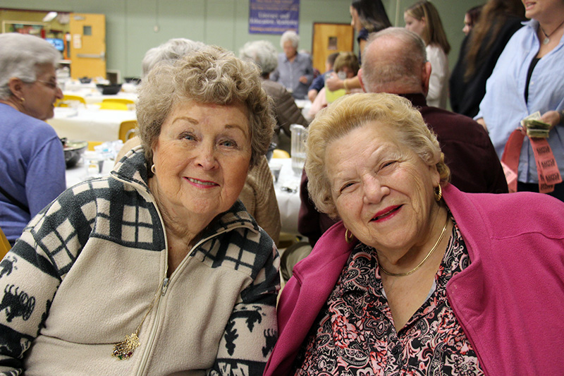 Two women smile.