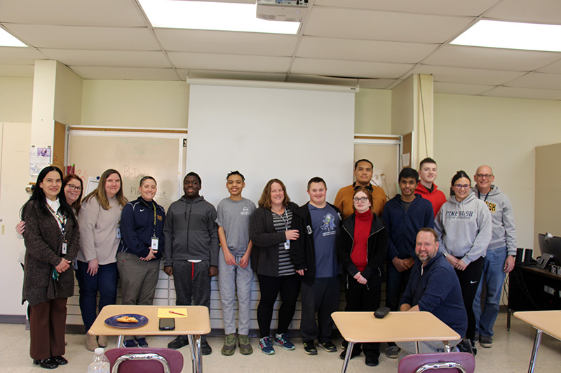 A large group stands together smiling. 