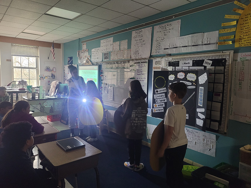 Students use a flashlight to show how an eclipse happens.