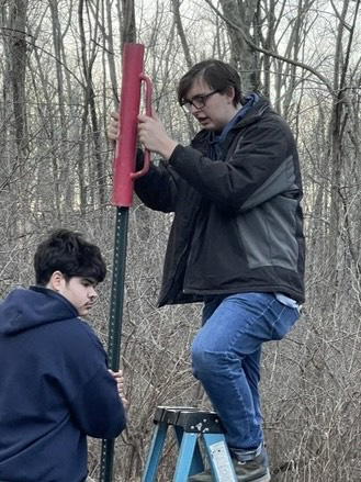 Two young men working on a post.